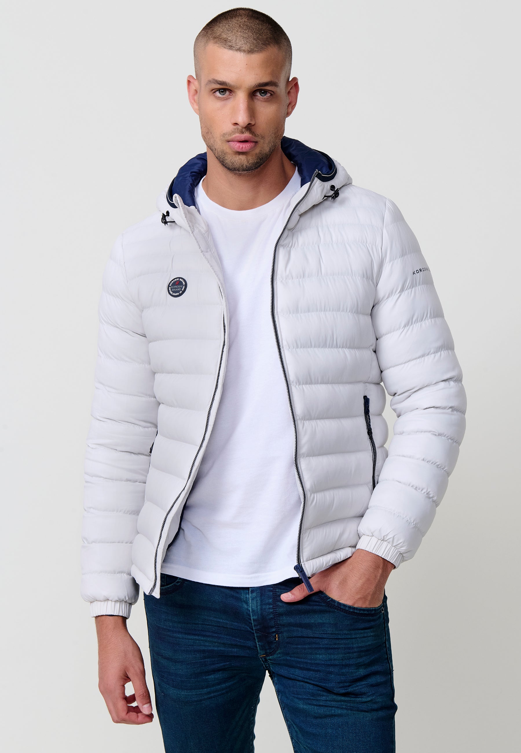 Piumino da uomo imbottito, collo alto, cappuccio, tasche e chiusura con cerniera.