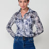 Chemise femme en mousseline semi-transparente avec imprimé floral, col chemise et fermeture boutonnée sur le devant.