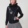 Sudadera abierta de mujer con capucha, tejido doble cara, interior polar, cremallera diagonal y bordado floral en el frontal y manga.