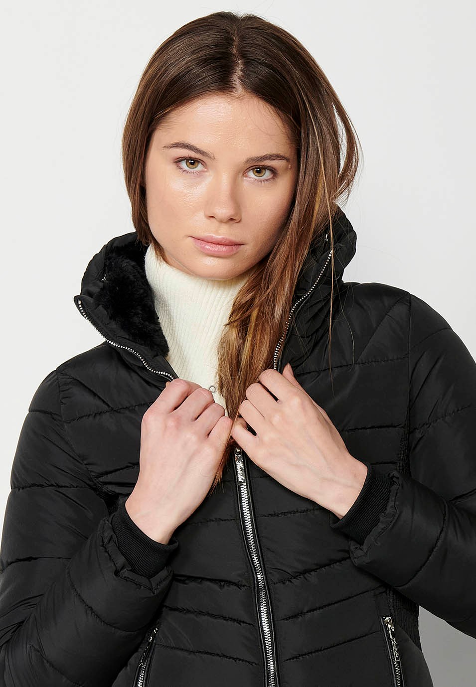 Parka acolchada corta con cuello alto y cierre delantero con cremallera y bolsillos de color negro para mujer