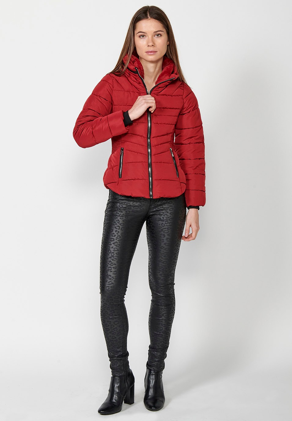 Parka acolchada corta con cuello alto y cierre delantero con cremallera y bolsillos de color rojo para mujer.