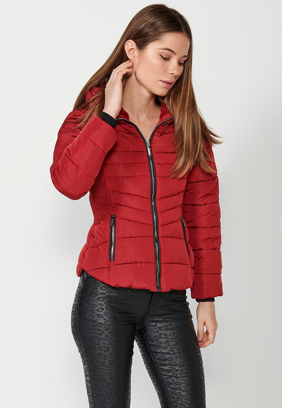 Parka acolchada corta con cuello alto y cierre delantero con cremallera y bolsillos de color rojo para mujer.