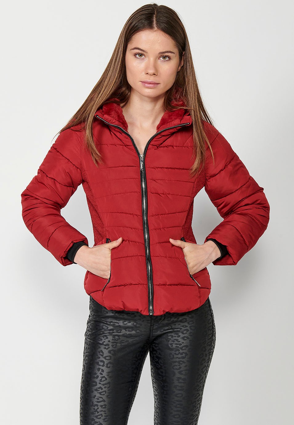 Parka acolchada corta con cuello alto y cierre delantero con cremallera y bolsillos de color rojo para mujer.