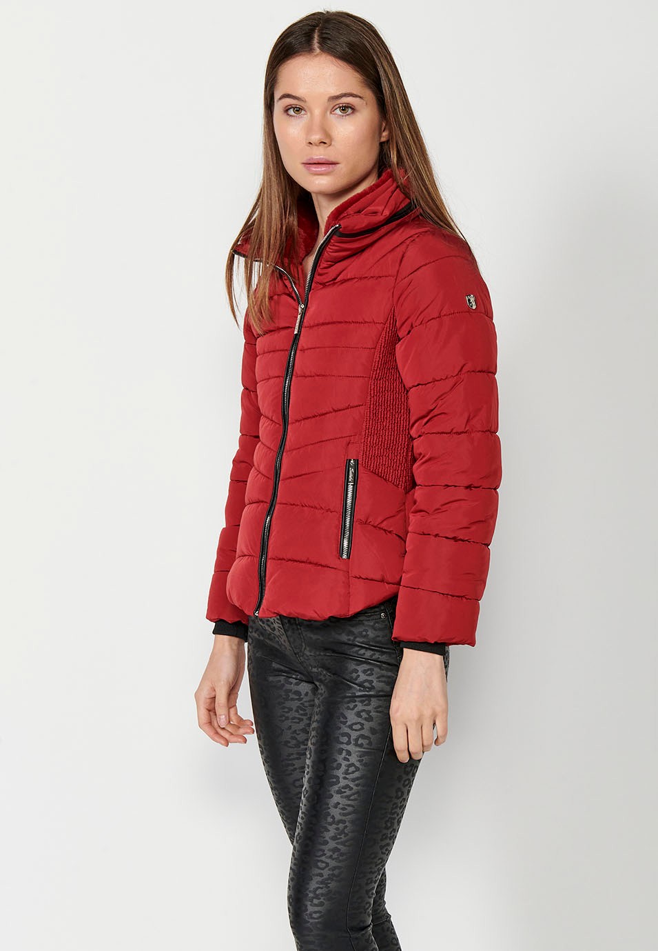 Parka courte rembourrée avec col montant et fermeture éclair sur le devant et poches rouges pour femme.