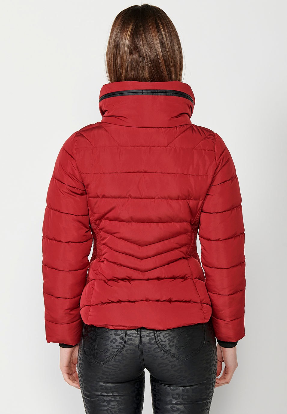 Parka acolchada corta con cuello alto y cierre delantero con cremallera y bolsillos de color rojo para mujer.