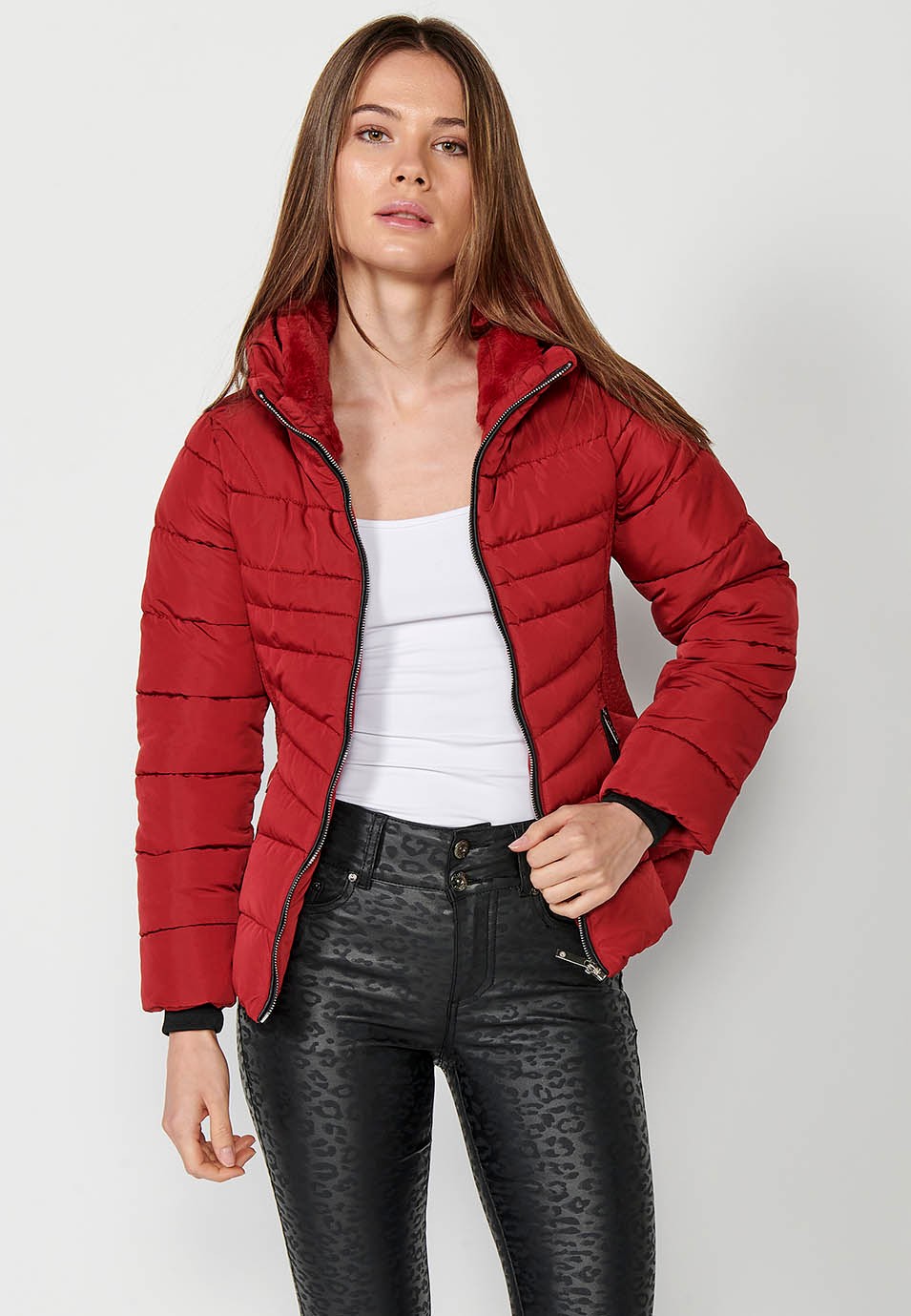 Parka acolchada corta con cuello alto y cierre delantero con cremallera y bolsillos de color rojo para mujer.