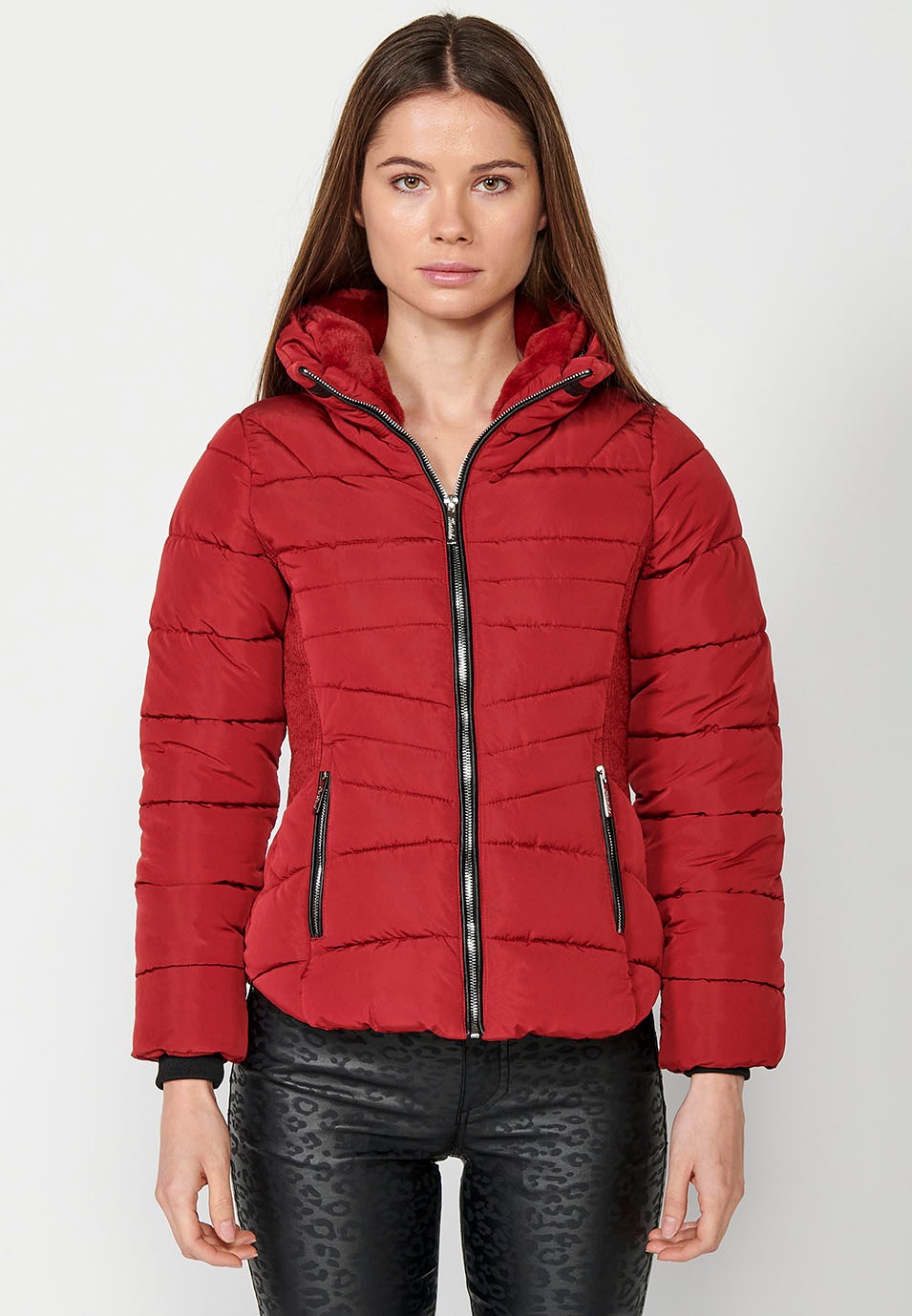 Parka courte rembourrée avec col montant et fermeture éclair sur le devant et poches rouges pour femme.