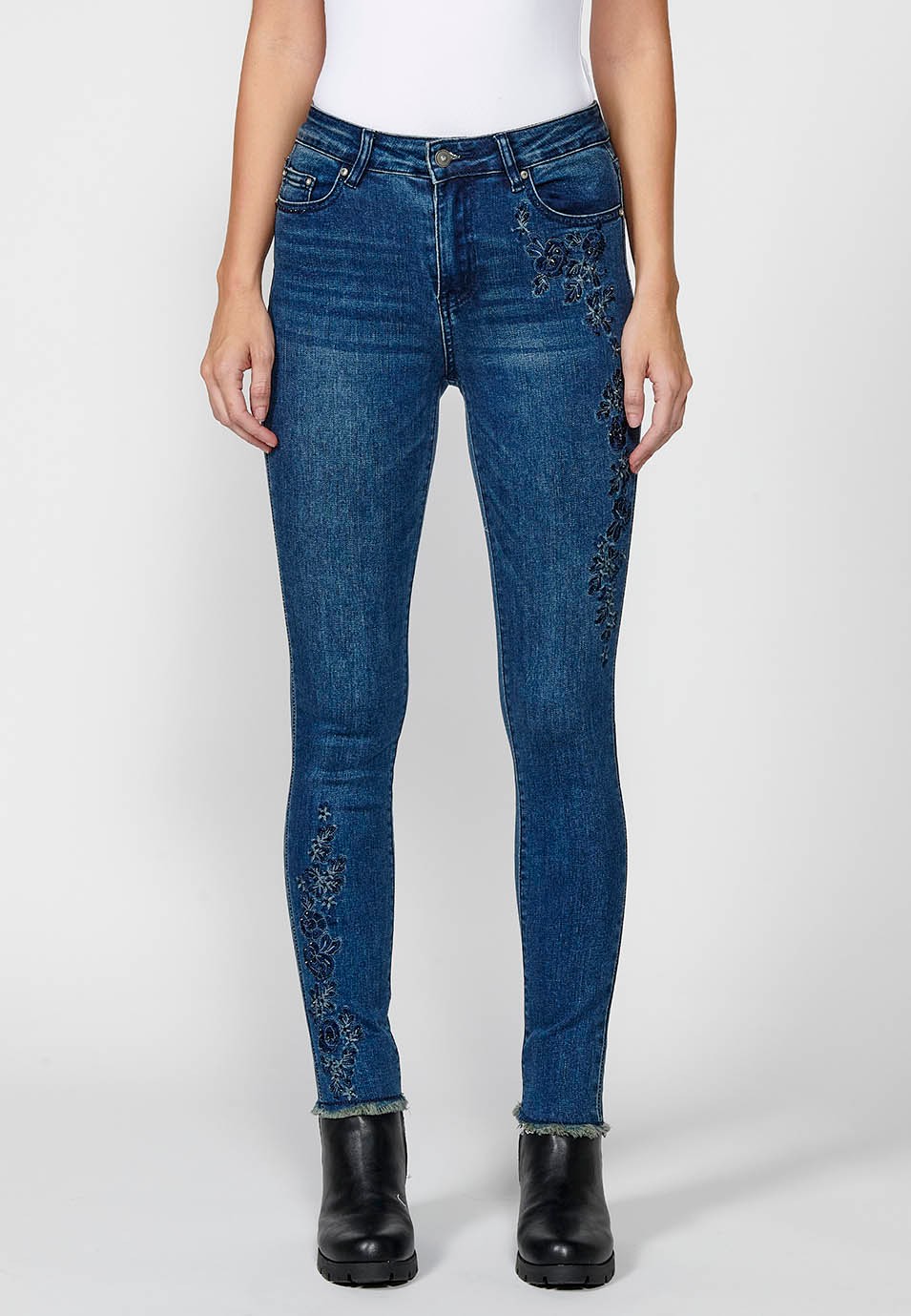 Pantalón largo denim slim cropped con cinco bolsillos y cierre delantero con cremallera y botón con detalles bordados florales para mujer de color azul