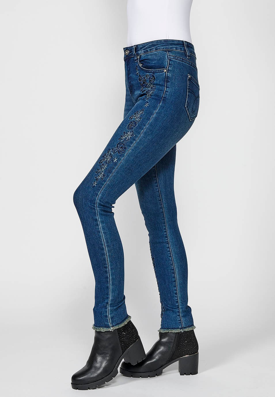 Pantalón largo denim slim cropped con cinco bolsillos y cierre delantero con cremallera y botón con detalles bordados florales para mujer de color azul