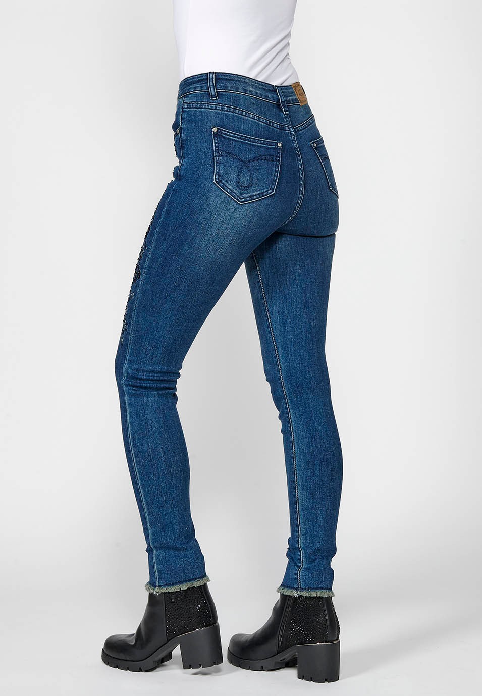 Pantalón largo denim slim cropped con cinco bolsillos y cierre delantero con cremallera y botón con detalles bordados florales para mujer de color azul