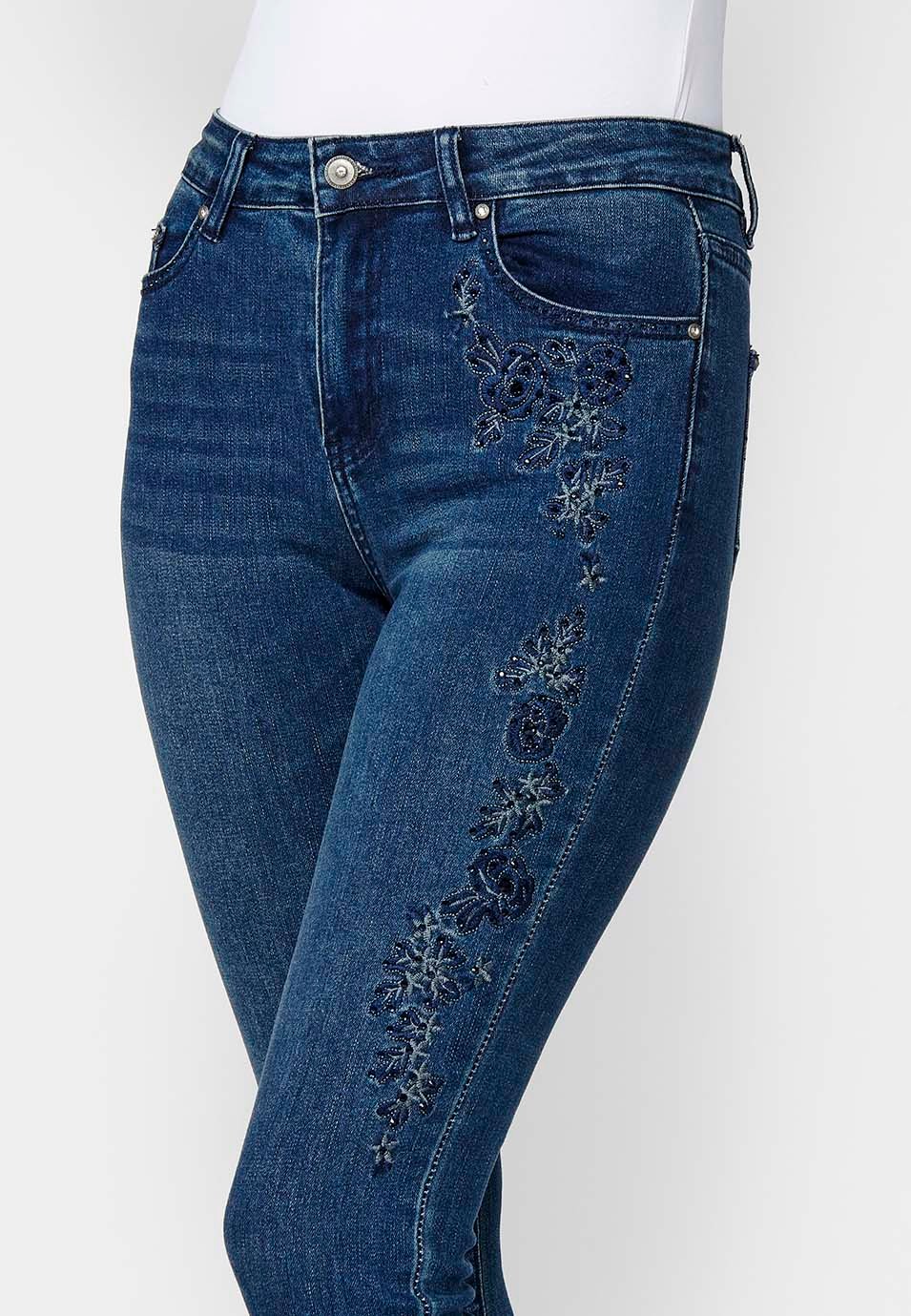 Pantalón largo denim slim cropped con cinco bolsillos y cierre delantero con cremallera y botón con detalles bordados florales para mujer de color azul