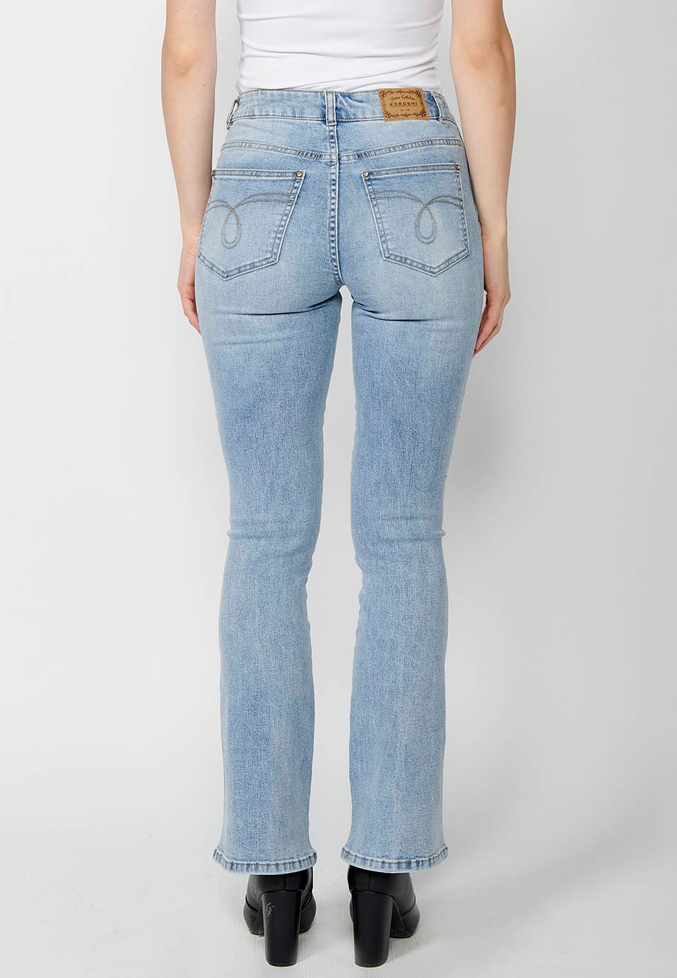 Pantalón denim cinco bolsillos campana de color azul con aplicaciones metálicas en bolsillos para mujer