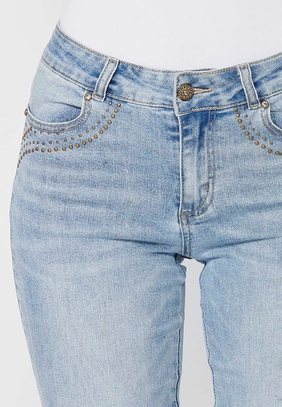 Pantalón denim cinco bolsillos campana de color azul con aplicaciones metálicas en bolsillos para mujer