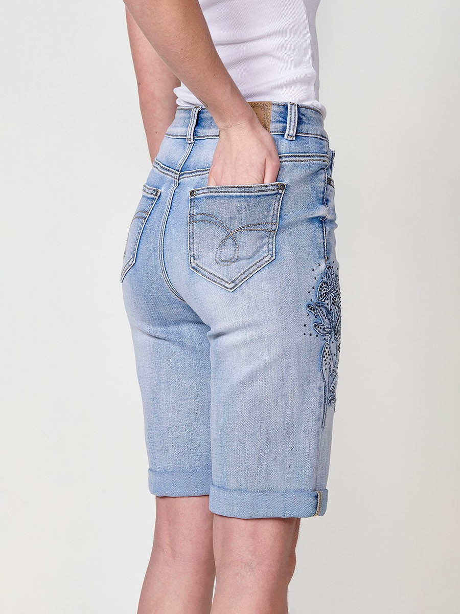 Jeans short elástico color lavado azul claro de Tiro medio y cinco bolsillos con Cierre con cremallera y botón metálico tiene el Bajo con doble vuelta y Patch de tejidos bordado y deshilachado con brillos para Mujer