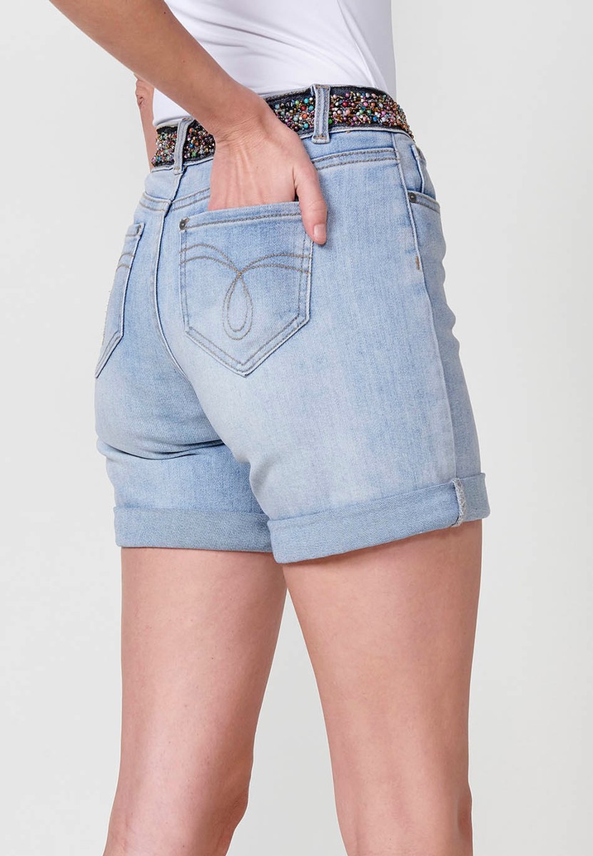 Jeans short elástico tiro medio y cinco bolsillos con abalorios de colores en cintura y cierre con cremallera y botón metálico con bajos con doble vuelta para mujer de color azil calaro