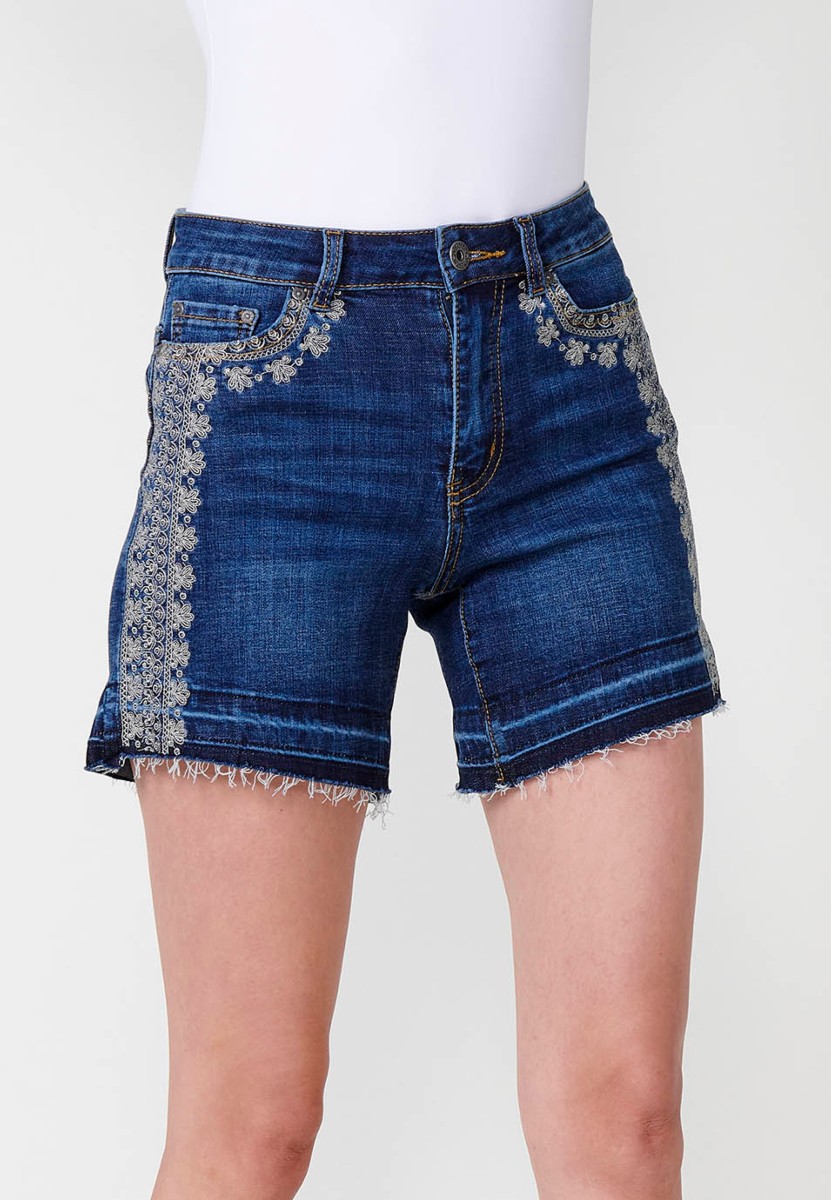 Jeans short elástico cenefa bordada en bolsillo y lateral de tiro medio y cinco bolsillos con cierre con cremallera y botón metálico y bajo deshilachado para mujer de color azul oscuro