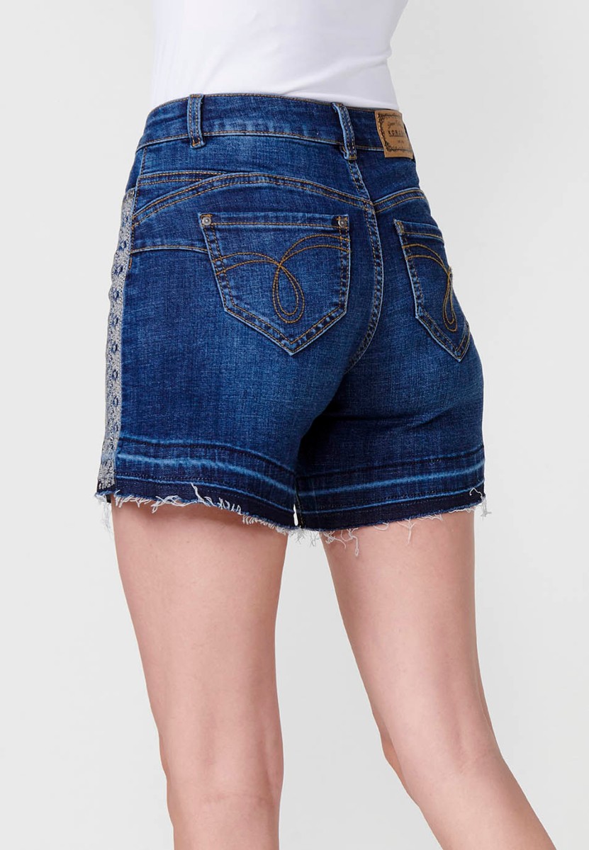 Jeans short elástico cenefa bordada en bolsillo y lateral de tiro medio y cinco bolsillos con cierre con cremallera y botón metálico y bajo deshilachado para mujer de color azul oscuro