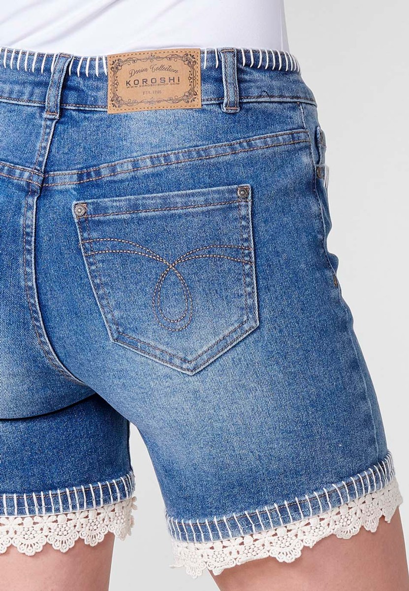 Jeans short elástico de tiro medio y cinco bolsillos con cierre con cremallera y botón metálico y detalle de pespuntes hechos a mano en bolsillos, cinturilla y bajo para mujer de color azul medio