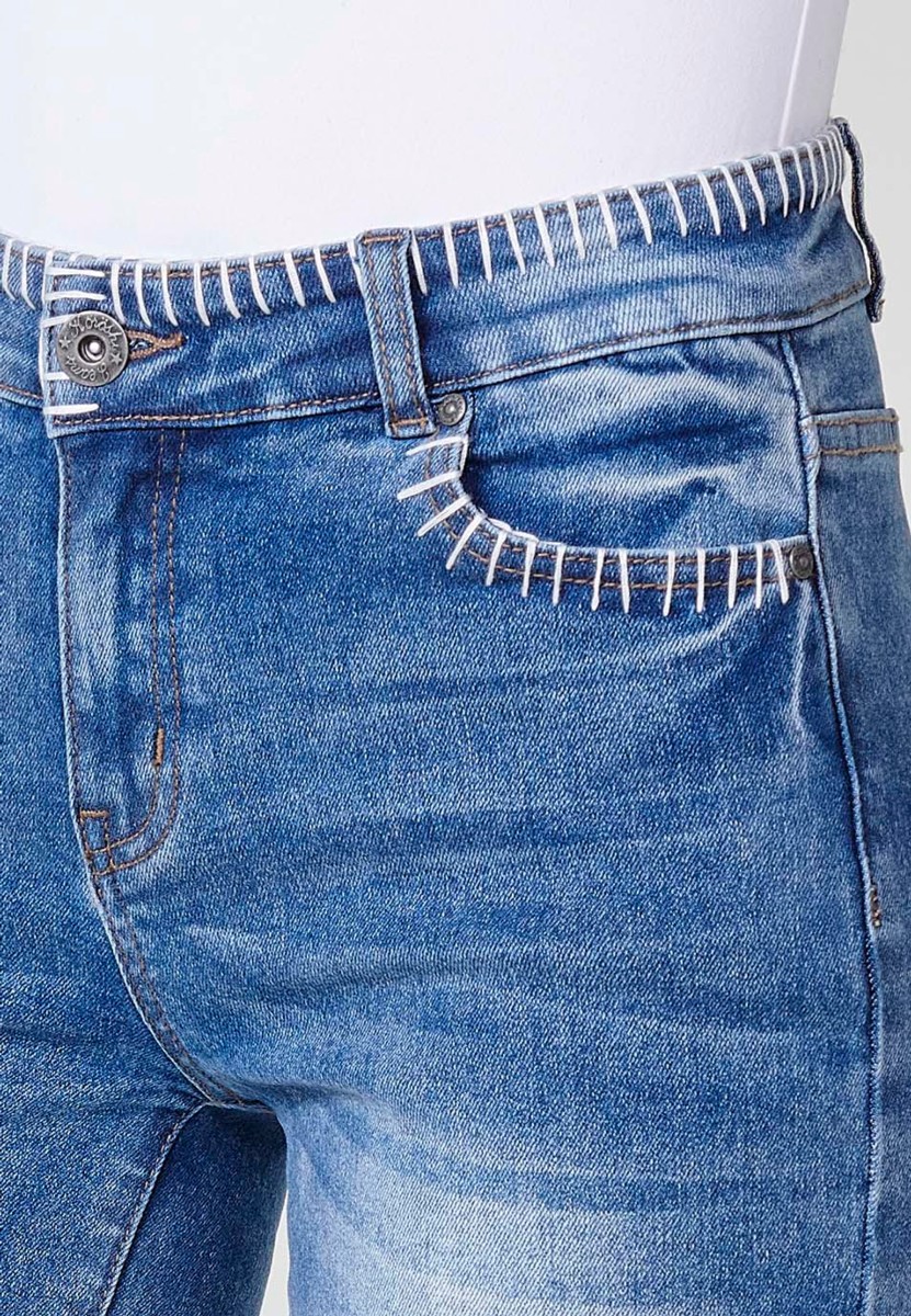 Jeans short elástico de tiro medio y cinco bolsillos con cierre con cremallera y botón metálico y detalle de pespuntes hechos a mano en bolsillos, cinturilla y bajo para mujer de color azul medio