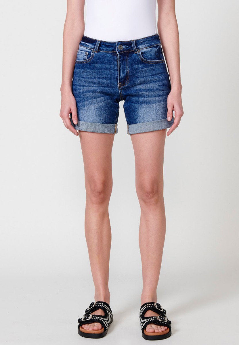 Jeans short elástico de tiro medio y cinco bolsillos con cierre con cremallera y botón metálico con bajo doble vuelta y logo con brillos para mujer de color azul oscuro