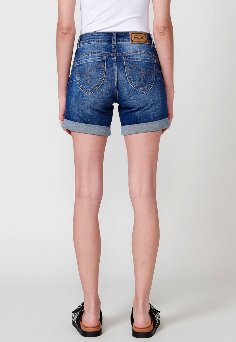 Jeans short elástico de tiro medio y cinco bolsillos con cierre con cremallera y botón metálico con bajo doble vuelta y logo con brillos para mujer de color azul oscuro