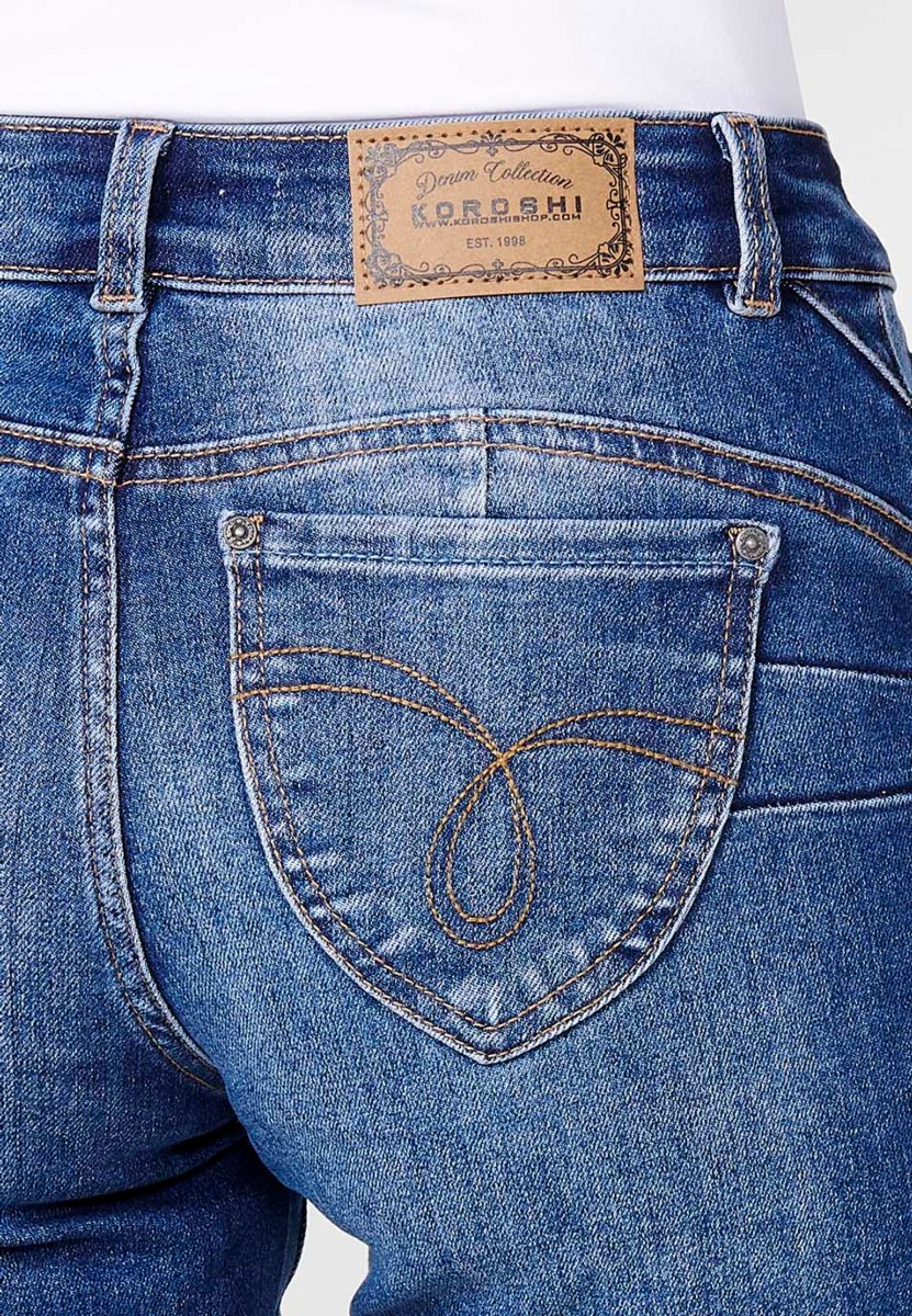 Jeans short elástico de tiro medio y cinco bolsillos con cierre con cremallera y botón metálico con bajo doble vuelta y logo con brillos para mujer de color azul oscuro