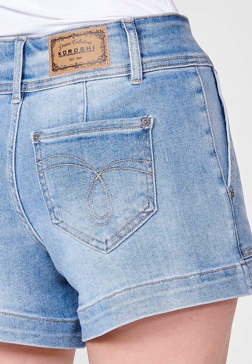 Short jean elásticocon bolsillos delanteros y traseros con cinturilla alta don doble botón metálico y cierre con cremallera con logo y brillos en bolsillo para mujer de color azul medio